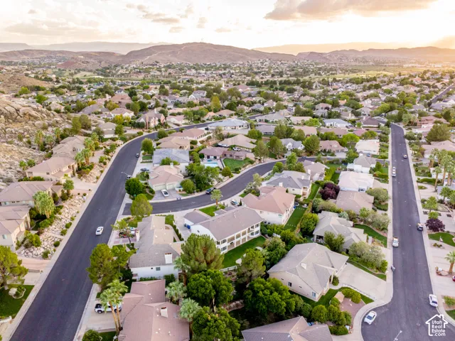 Aerial perspective of a developed neighborhood featuring residential properties with mature landscaping and mountain backdrops
