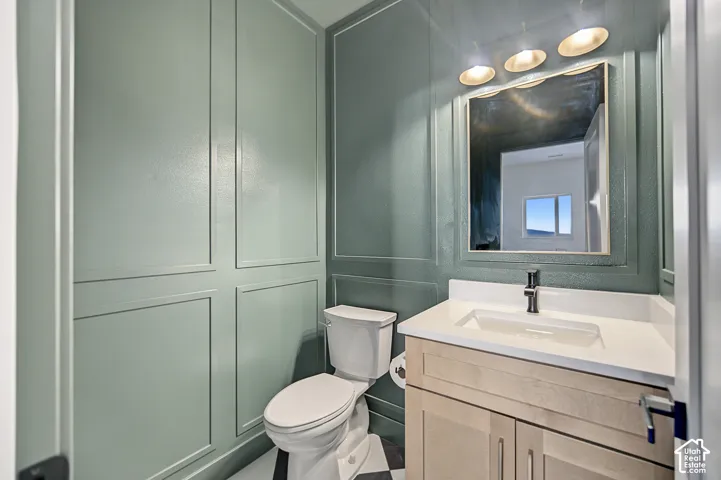 Board and batten wall detailing, vanity with light wood-finish cabinetry, integrated sink, and a contrasting dark faucet