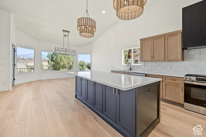 Spacious kitchen featuring a large island with a white countertop, two-tone cabinetry, stainless steel appliances, and wood-finish flooring