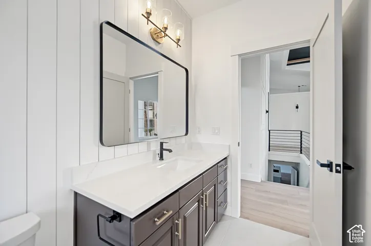 White shiplap accent wall, vanity with white countertop, integrated sink, black framed mirror, and three-light vanity fixture