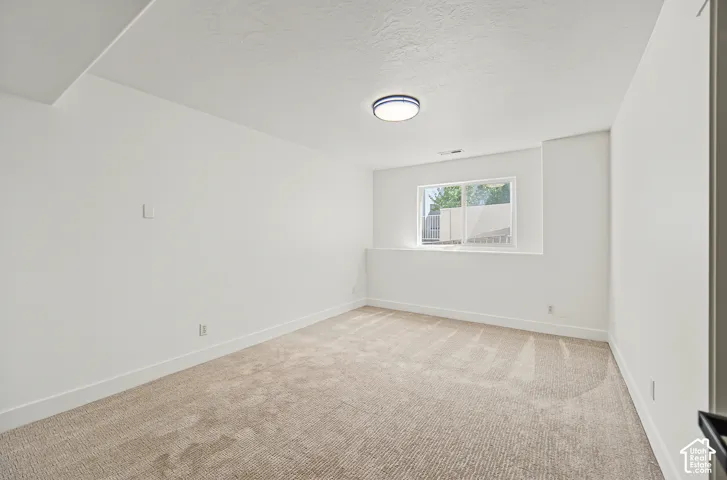 Neutral wall colors, recessed window, flush-mount ceiling light, and textured carpeting