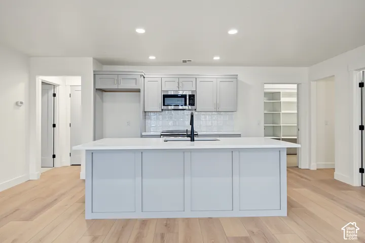 Kitchen featuring a central island, light-toned wood-finish flooring, recessed lighting, and a walk-in pantry with built-in shelving
