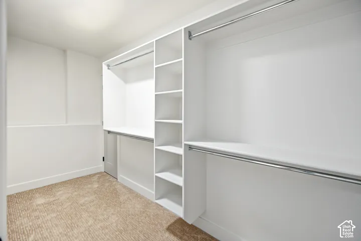Custom closet organization system with integrated shelving, multiple hanging rods, and a neutral-toned carpet