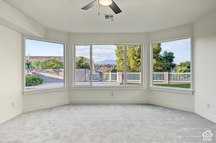 Room featuring expansive bay windows, neutral carpeting, a ceiling fan, and white walls