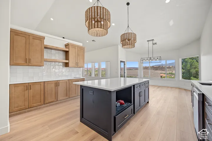 Spacious kitchen featuring light wood-finish flooring, a large island with built-in cabinetry, and a white countertop