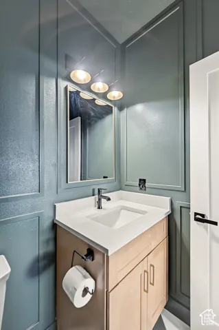 Wainscot paneling with a contemporary vanity, white countertop, and integrated sink