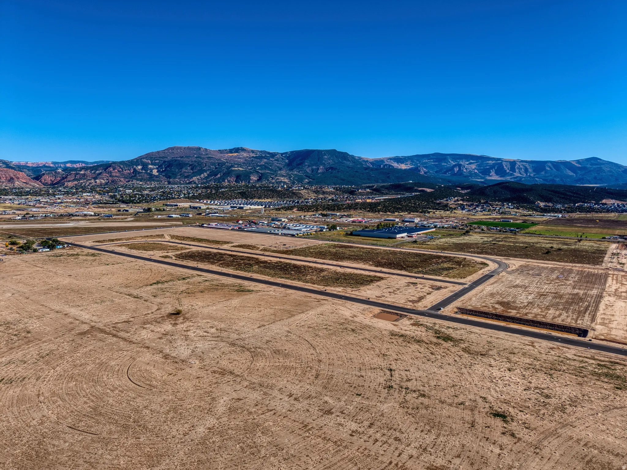 Expansive land parcel featuring new asphalt roadways, cleared development plots, and a mountainous backdrop