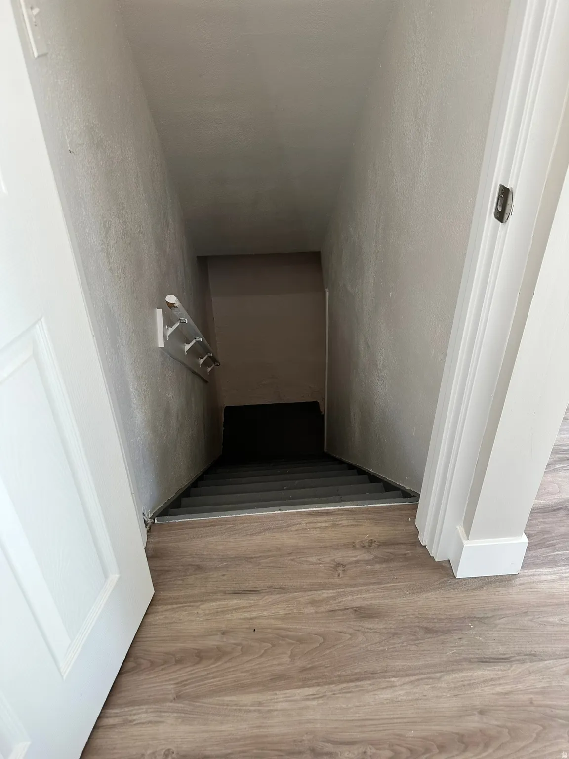Wood-finish flooring, white trim, and a descending staircase with gray treads