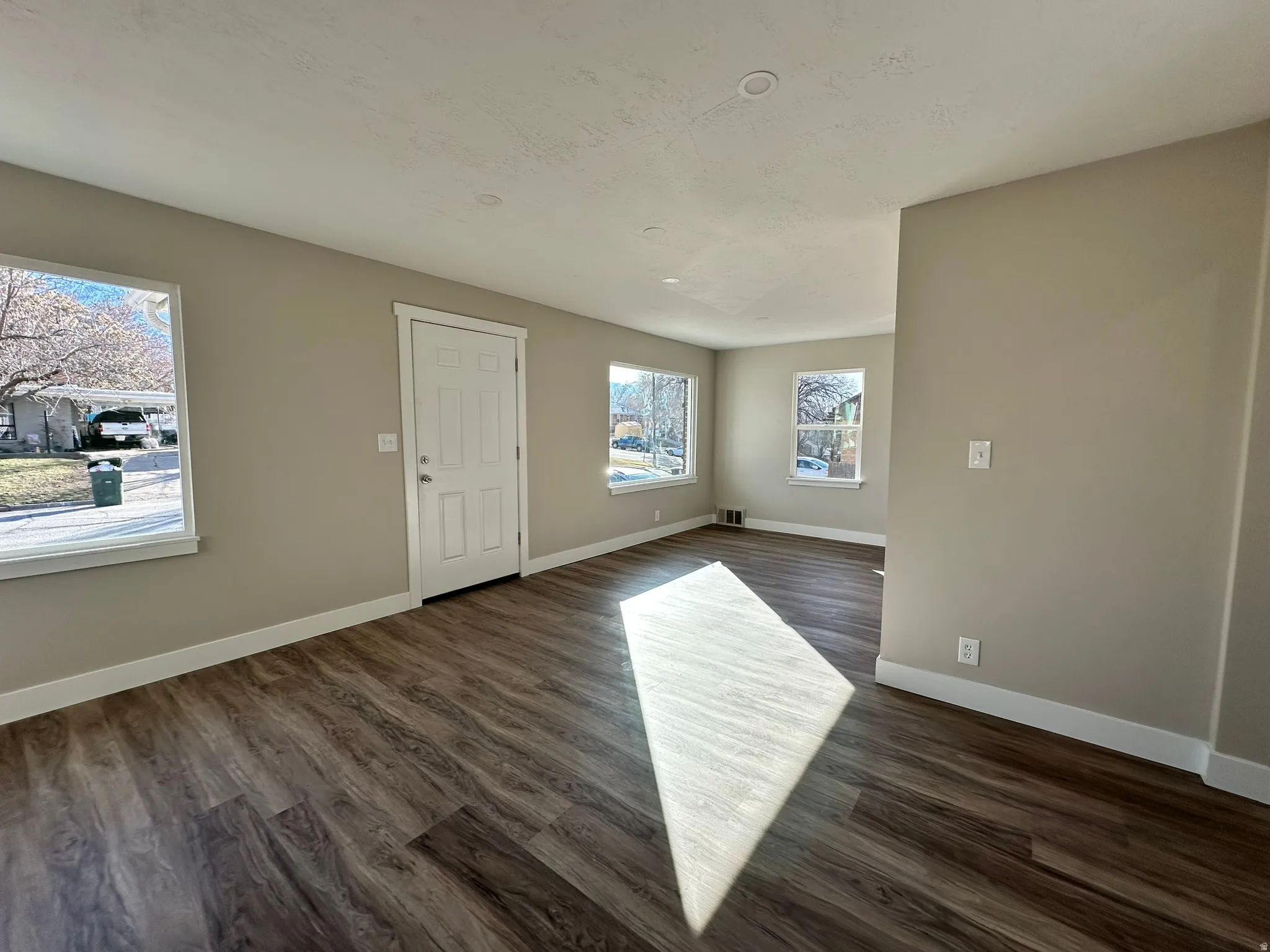 Wood-finish flooring, multiple windows, recessed lighting, white baseboards, and neutral wall tones
