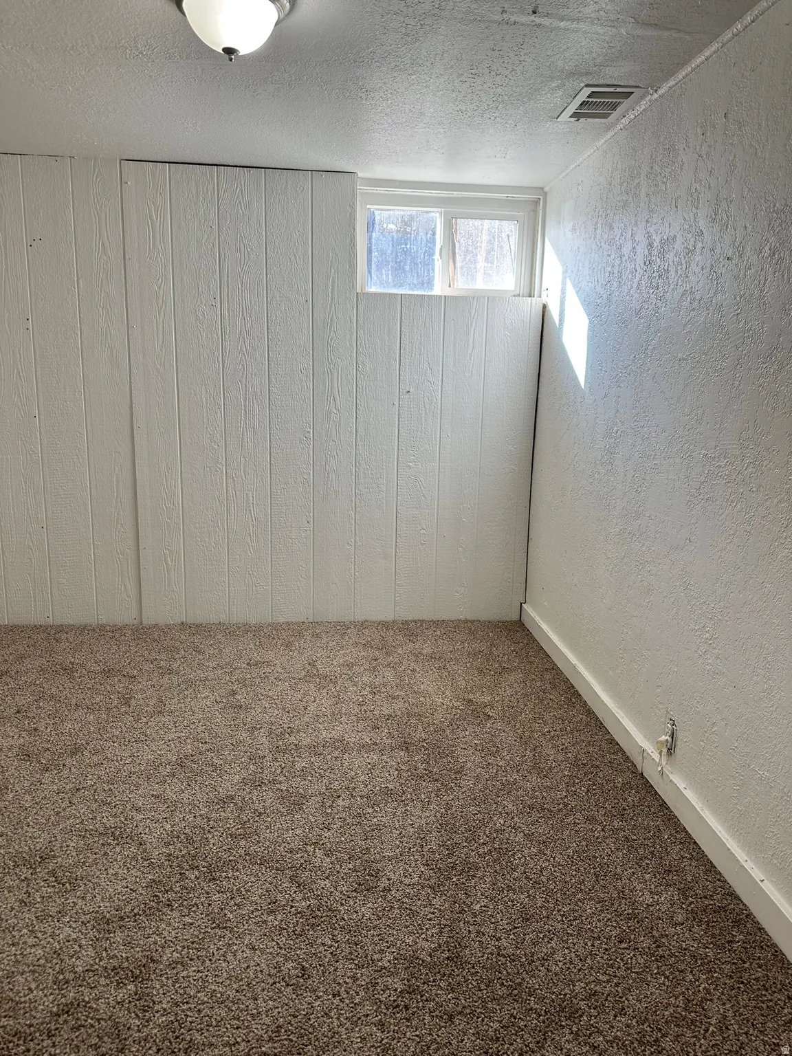 White paneled wall, textured wall finish, and window