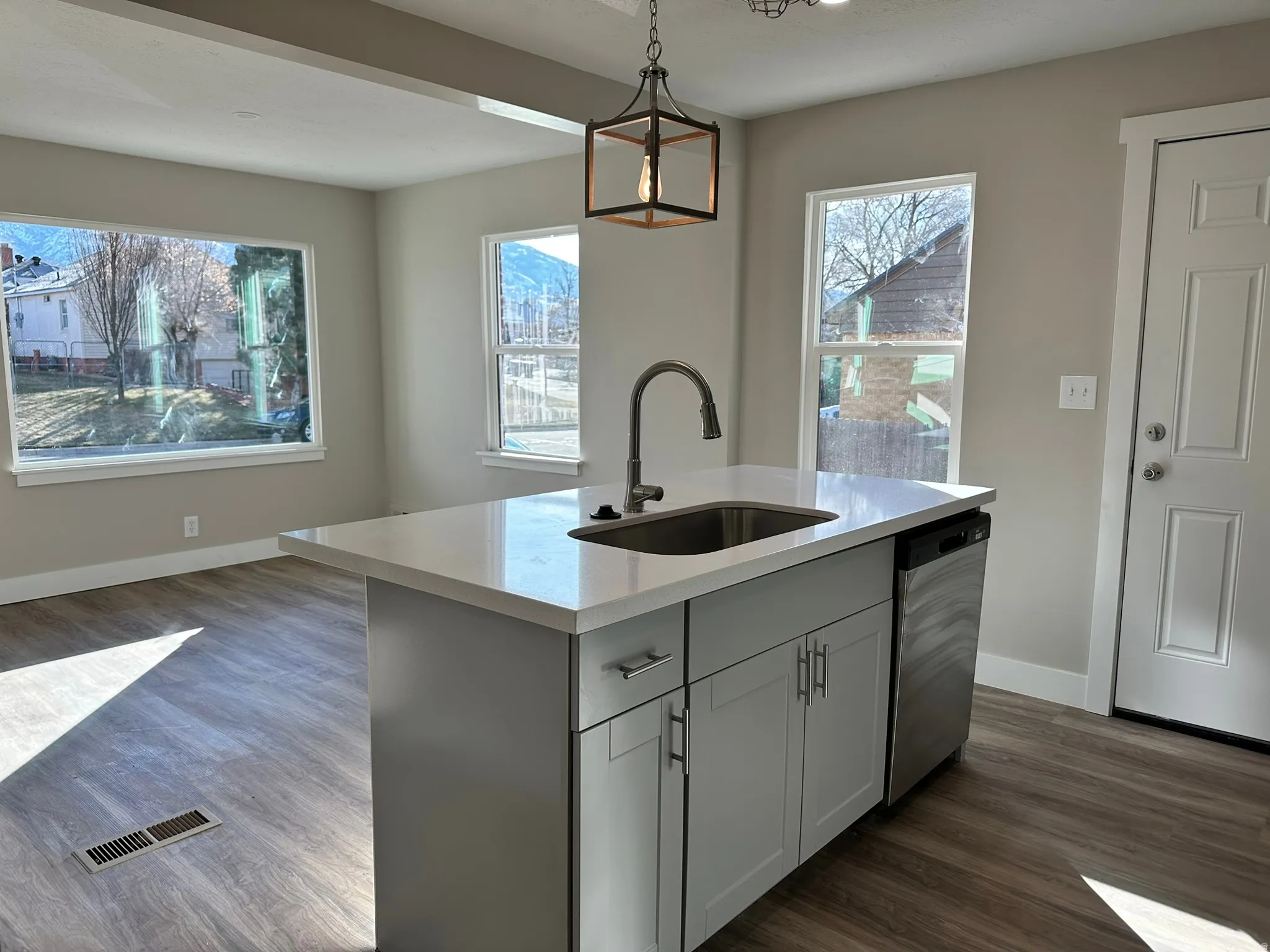 Kitchen island with a light-toned countertop, integrated sink, and stainless steel dishwasher