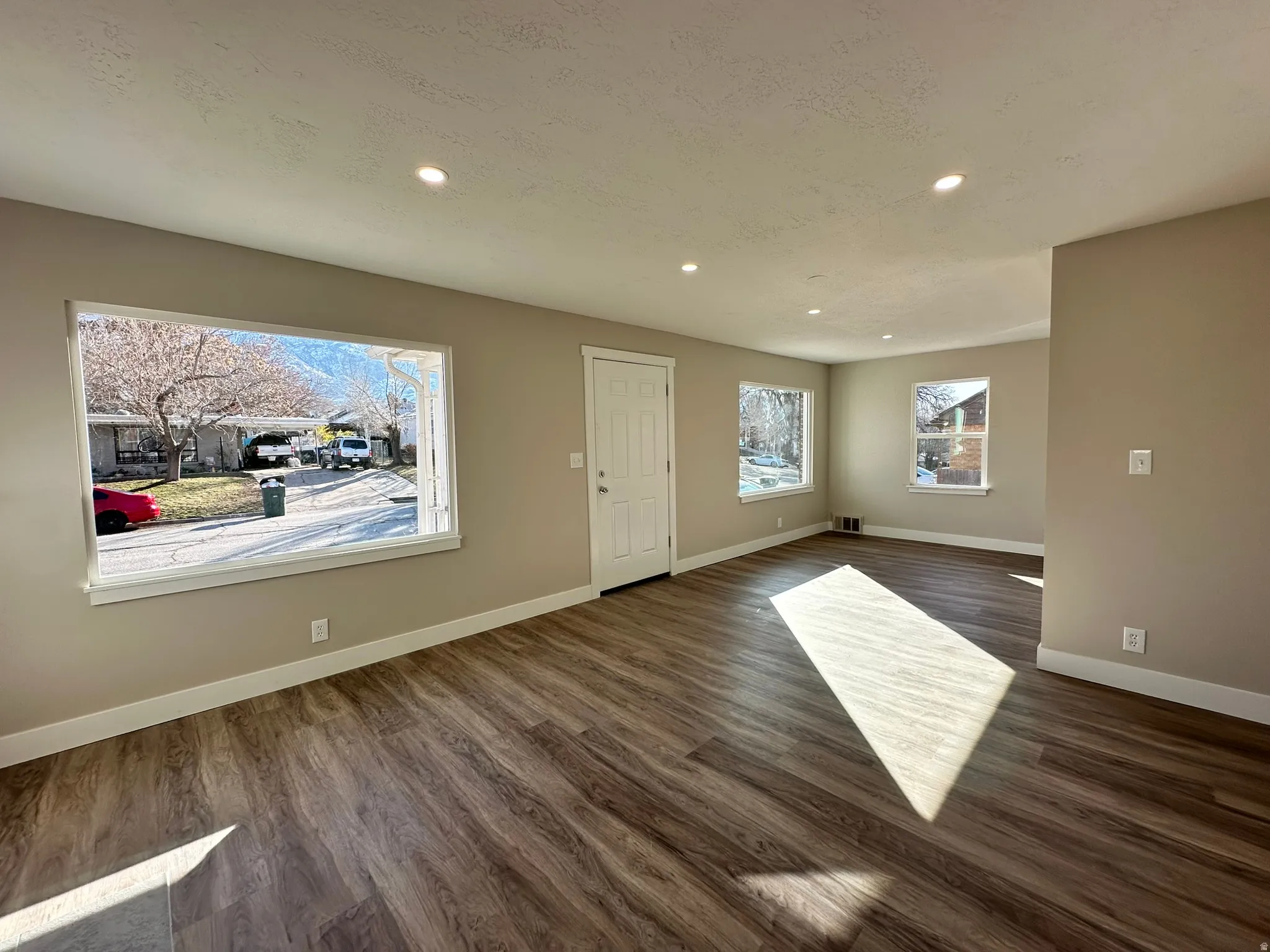 Recessed lighting, wood-finish flooring, neutral paint palette, and multiple windows