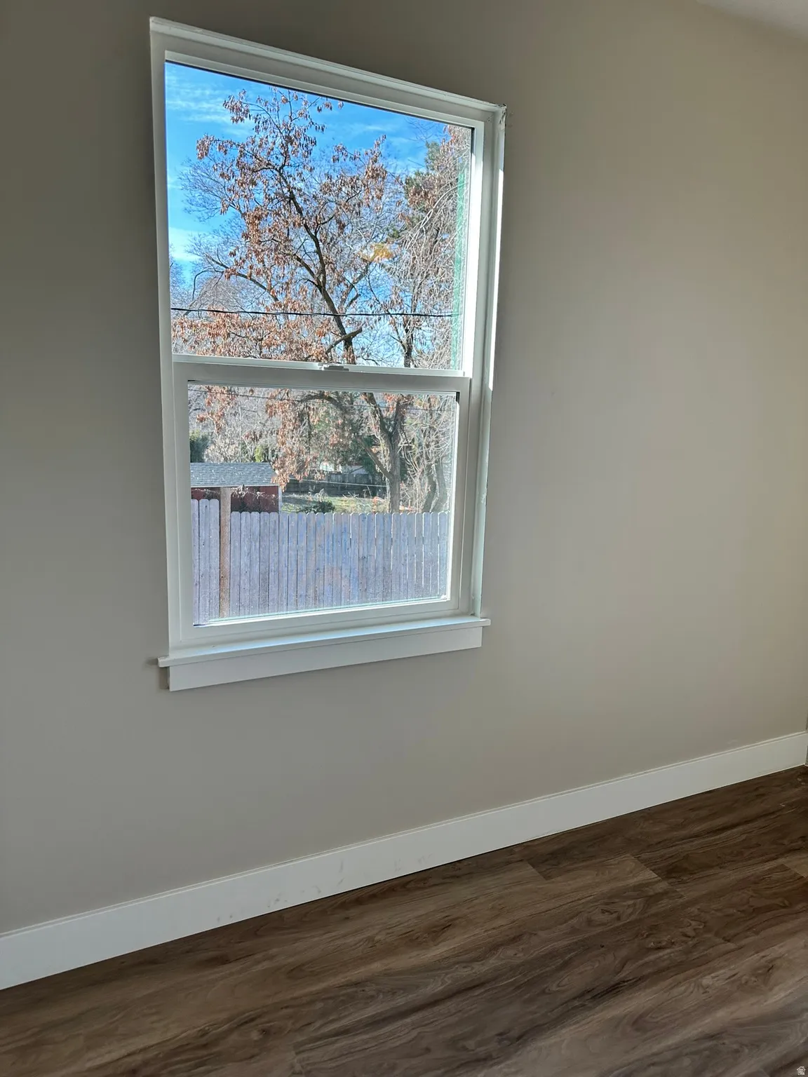 Double-hung window, crisp white trim, light neutral wall color, wood-finish flooring