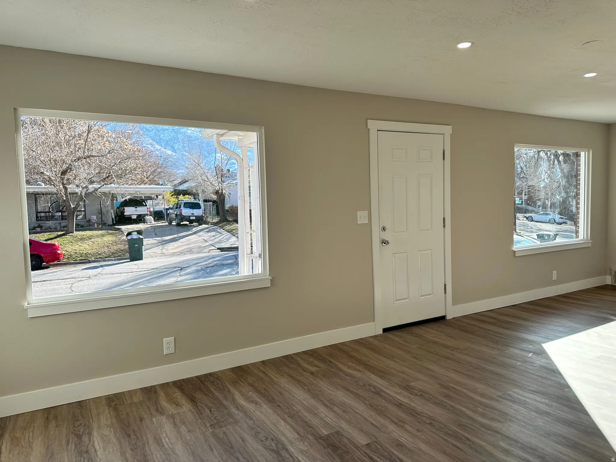 Wood-finish flooring, recessed lighting, and multiple windows with white trim
