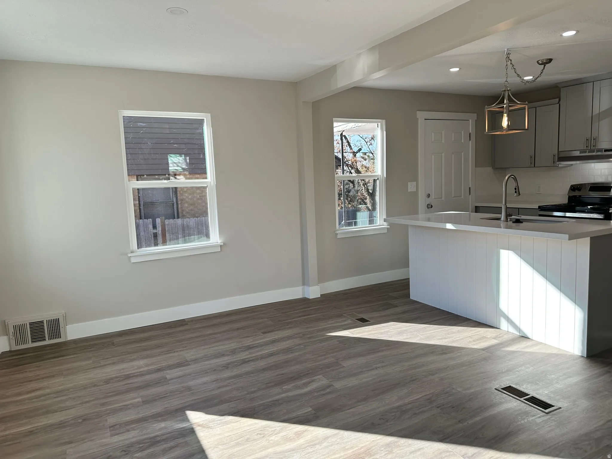Open-concept living space with wood-finish flooring, recessed lighting, and bright windows