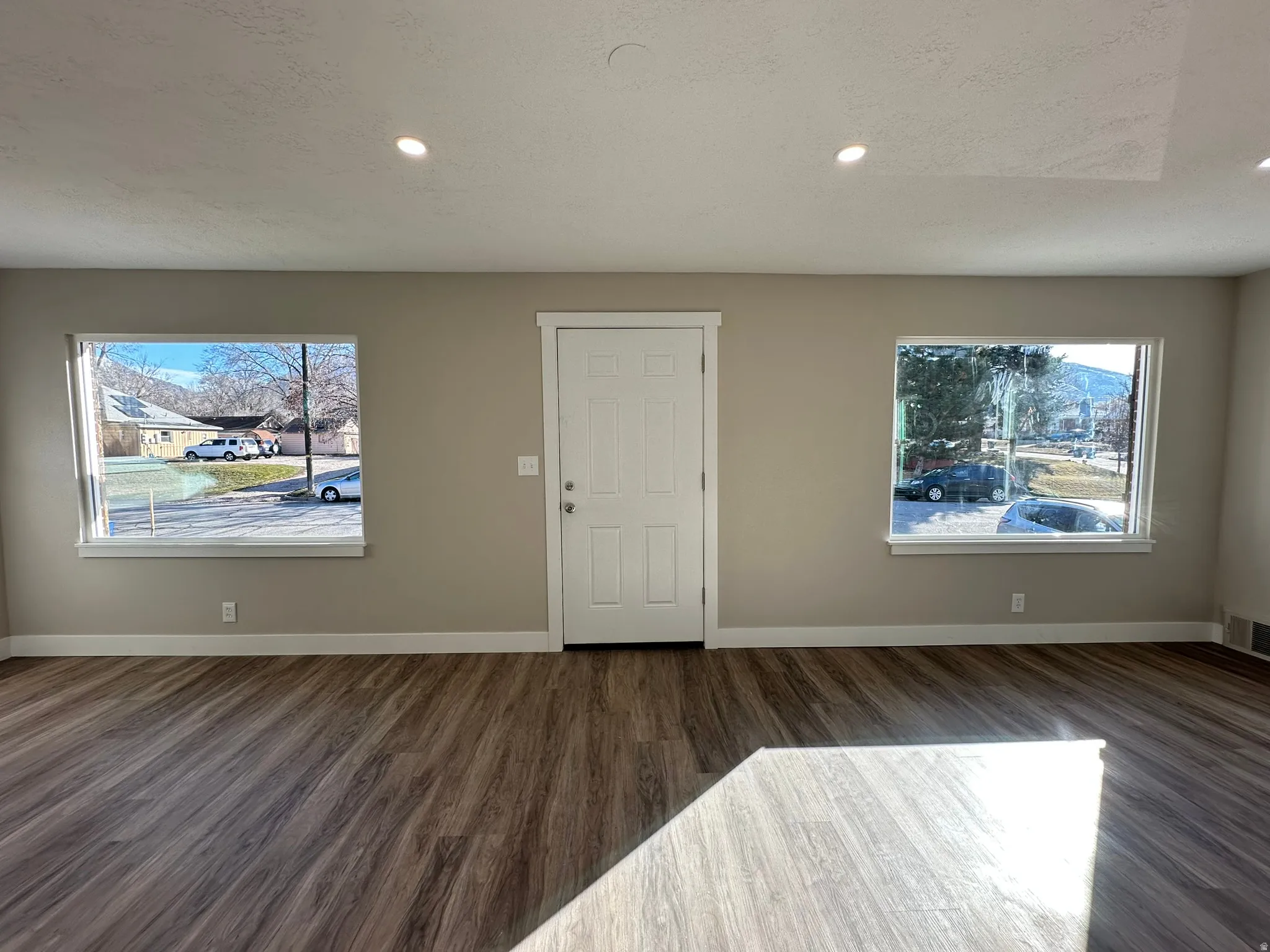 Wood-finish flooring, recessed lighting, and a white paneled entry door