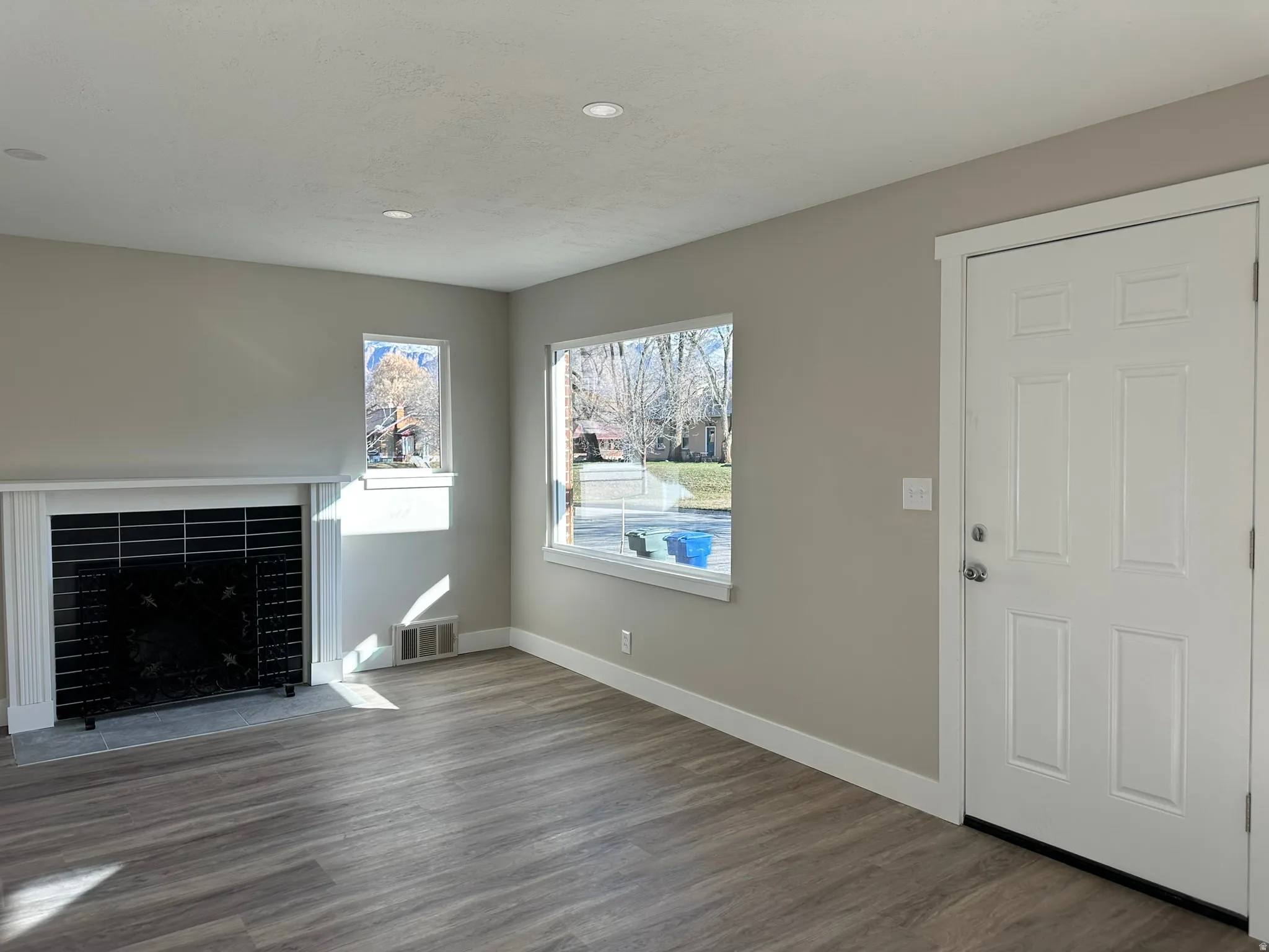 Wood-finish flooring, recessed lighting, and a white paneled entry door