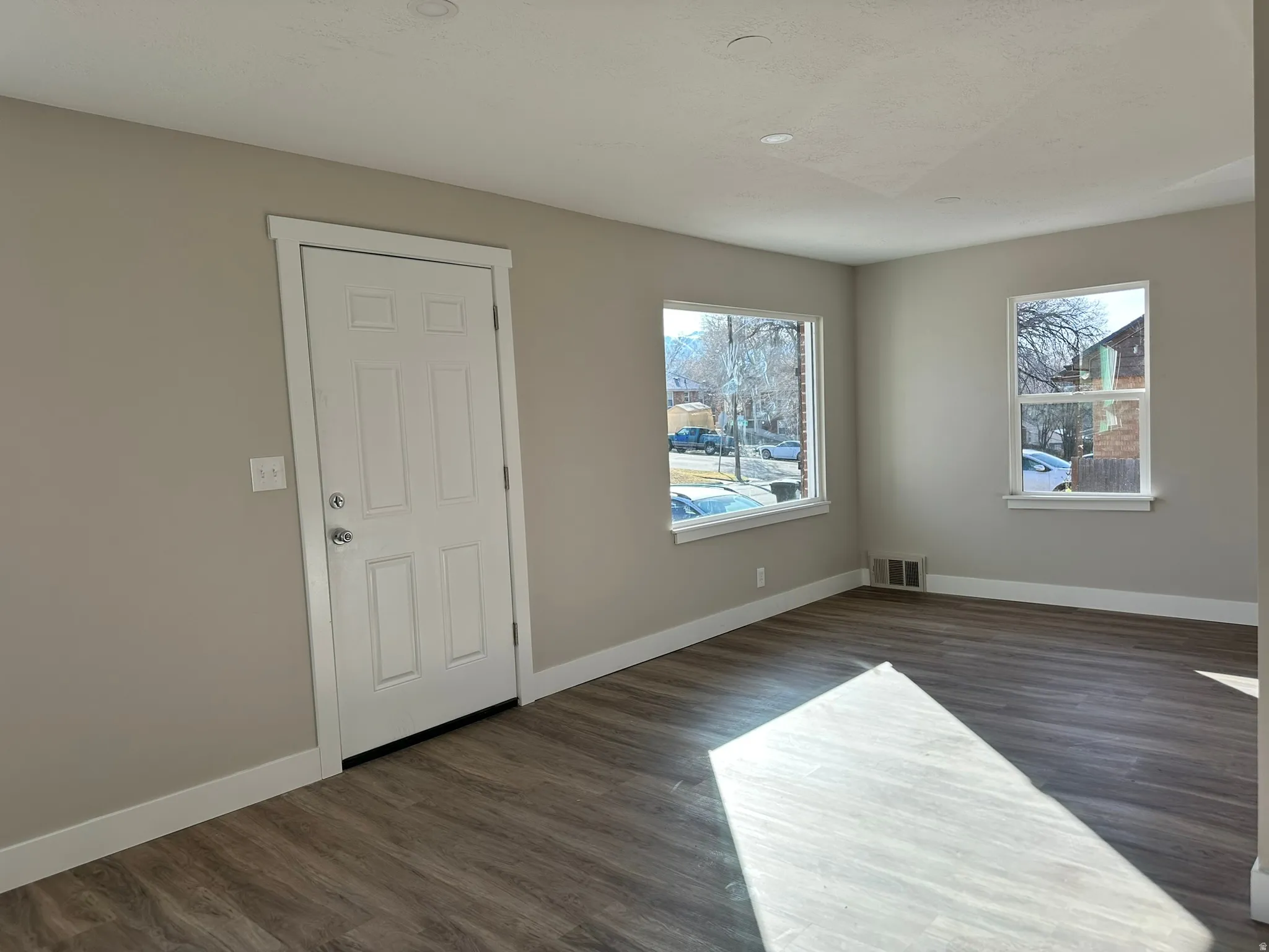 Wood-finish flooring, recessed lighting, and multiple windows with white trim