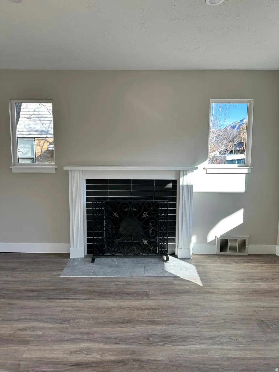 Fireplace with decorative screen, classic white mantel, tile hearth, and wood-finish flooring