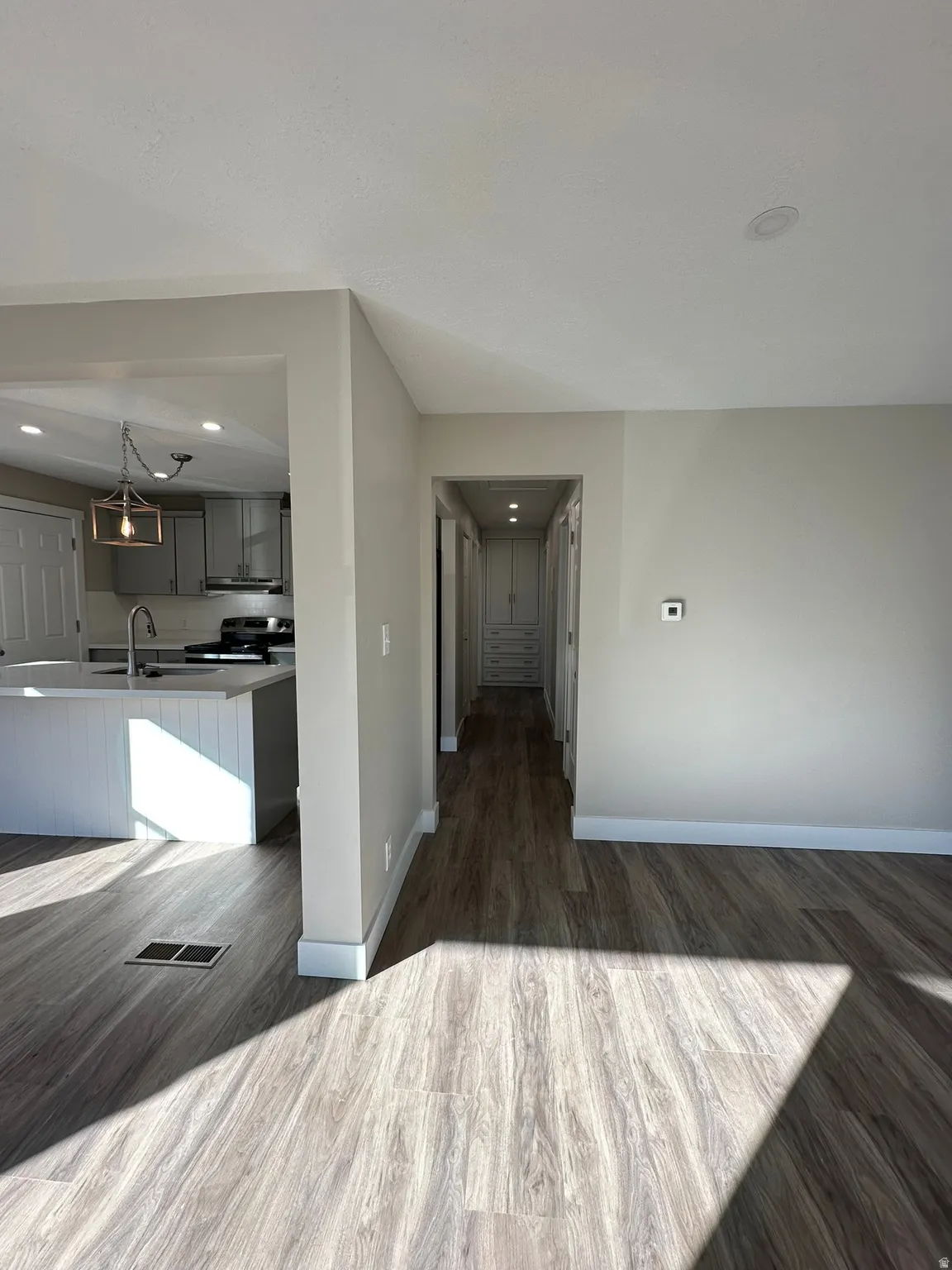 Open-concept design featuring wood-finish flooring, recessed lighting, and a kitchen island with a built-in sink