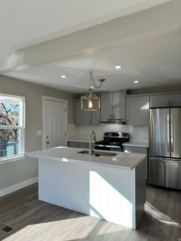Kitchen featuring wood-finish flooring, recessed lighting, a kitchen island with sink, stainless steel appliances, and gray cabinetry