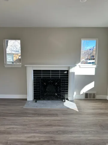 Fireplace with decorative screen, classic white mantel, tile hearth, and wood-finish flooring