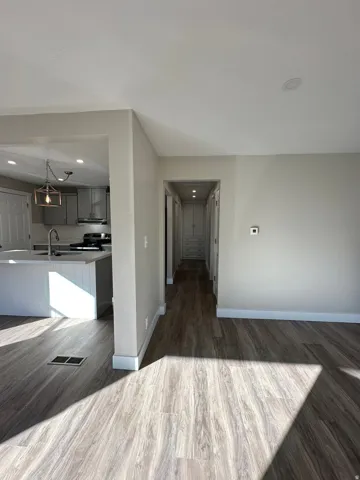 Open-concept design featuring wood-finish flooring, recessed lighting, and a kitchen island with a built-in sink