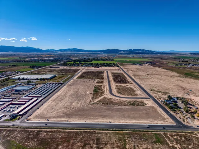 Expansive land parcel with established road infrastructure, visible mountain backdrop, and nearby commercial facilities