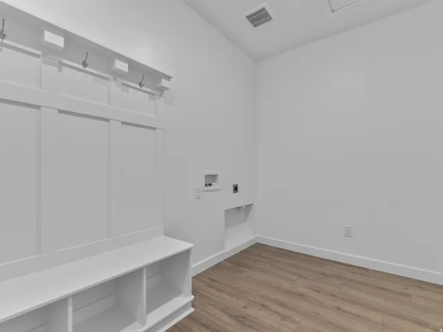 Mudroom featuring built-in bench seating, storage cubbies, and wall-mounted hooks