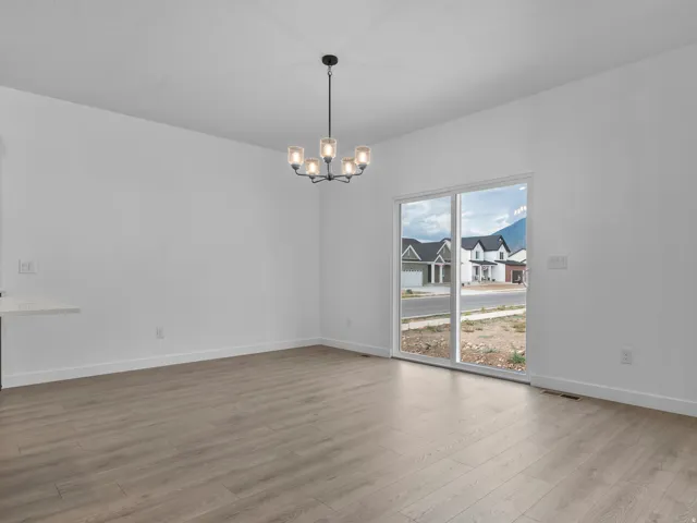 Wood-finish flooring, white walls, modern chandelier, and sliding glass door