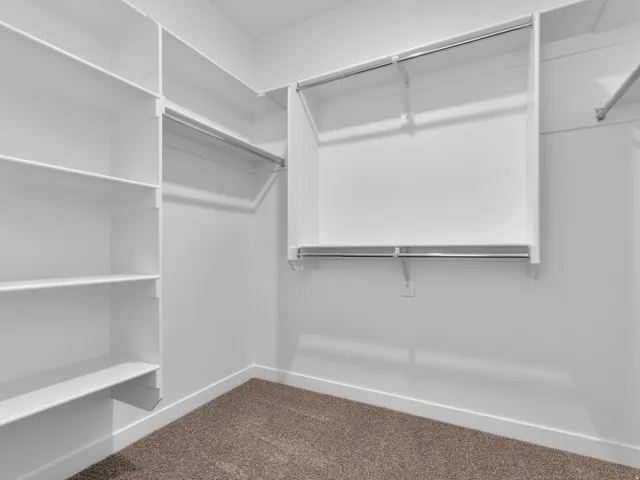 Custom closet system with multiple shelving units, chrome hanging rods, and neutral carpet flooring