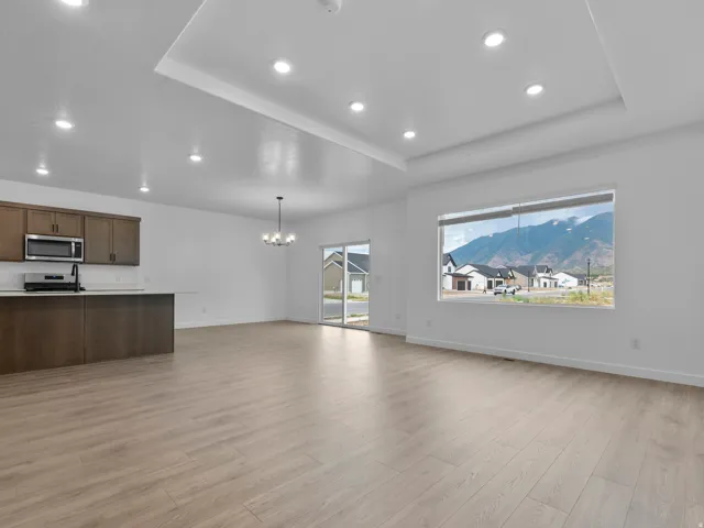 Open-concept living space featuring wood-finish flooring, recessed lighting, and a tray ceiling
