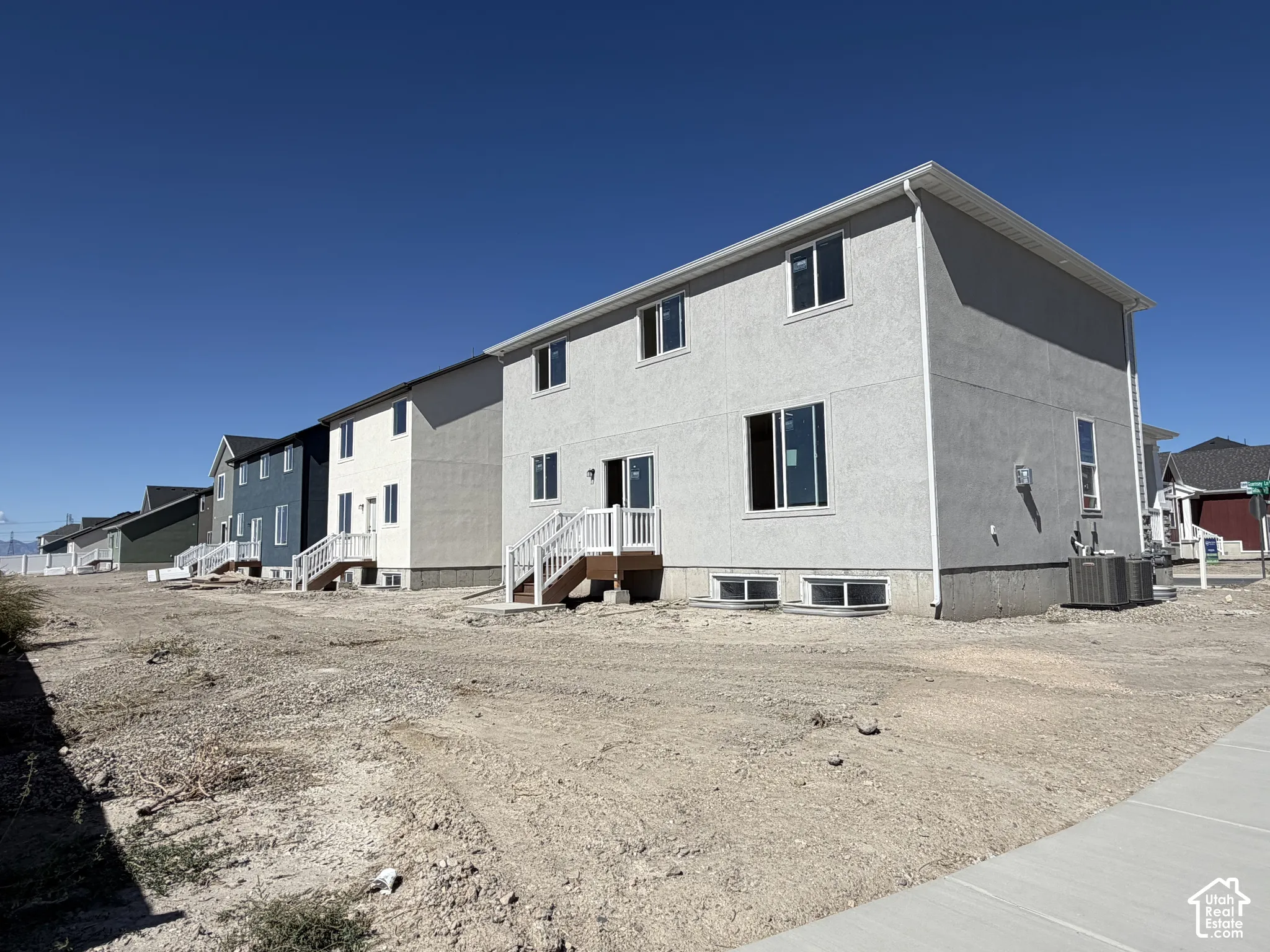 Two-story residence featuring light gray stucco exterior, white trim, and a rear deck with white railings