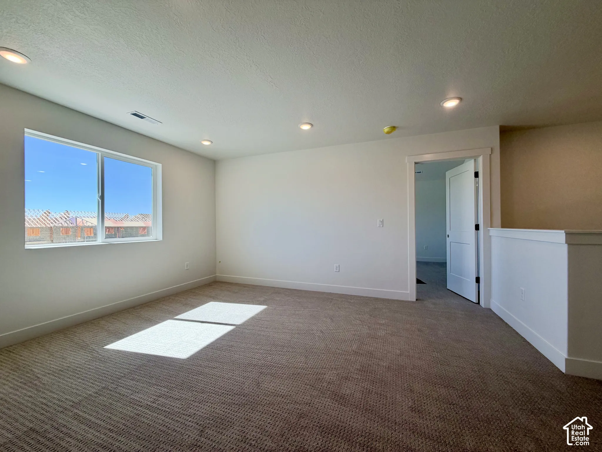 Recessed ceiling lighting, durable carpet flooring, a spacious window, and a modern interior door