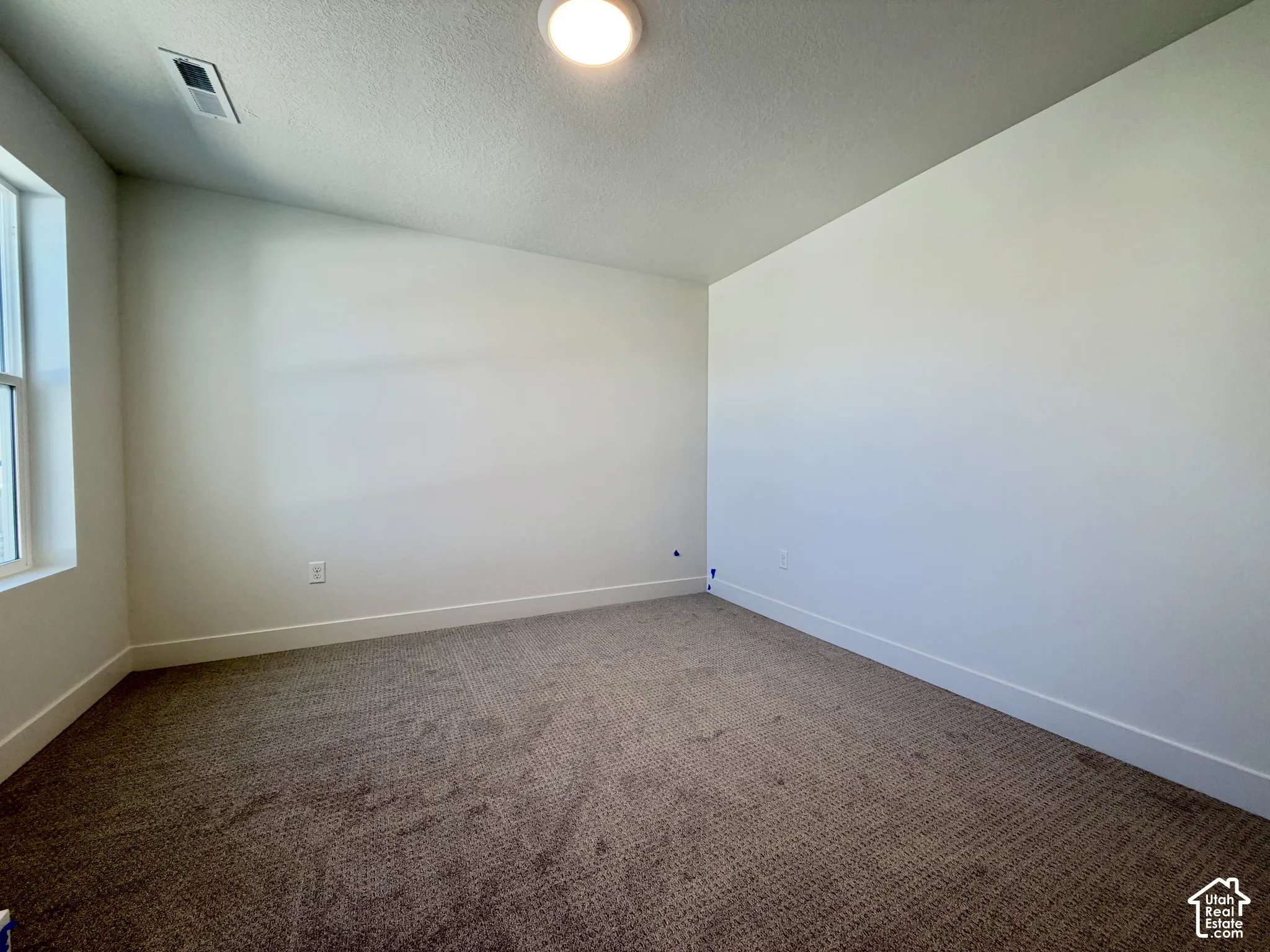 Recessed lighting, neutral wall tones, window for natural light, and textured carpeting