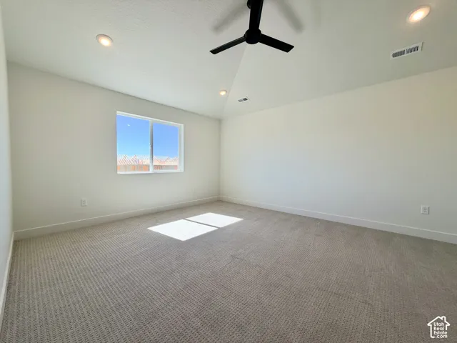 Recessed lighting, a ceiling fan, and a large window illuminate this carpeted room