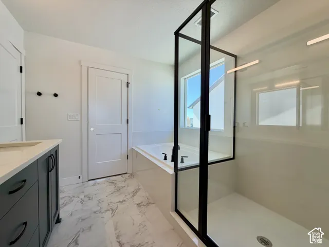 Freestanding soaking tub, glass-enclosed shower, dark-finish vanity with countertop, and large format floor tile