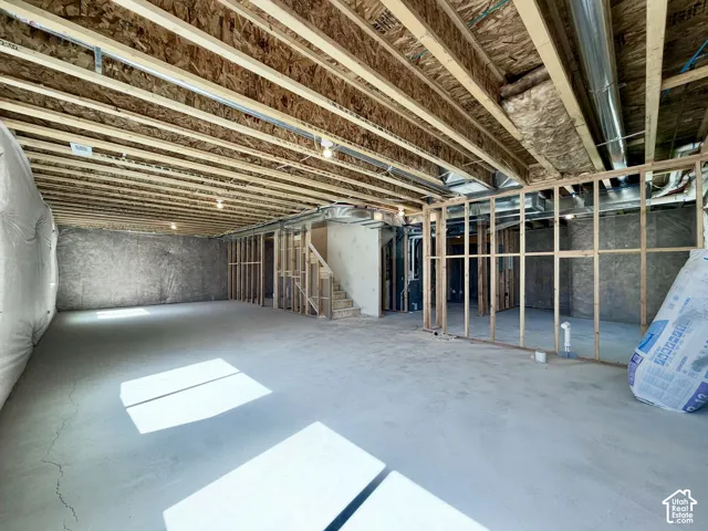 Unfinished lower level with concrete flooring, exposed wood joists, and framed partition walls