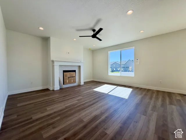 Spacious room featuring wood-finish flooring, a contemporary fireplace with decorative tile surround, recessed lighting, and a ceiling fan
