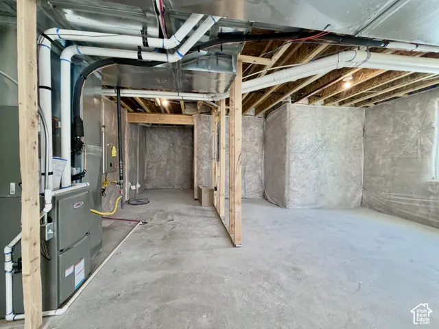 Unfinished basement featuring exposed ceiling joists, concrete flooring, and an installed HVAC system