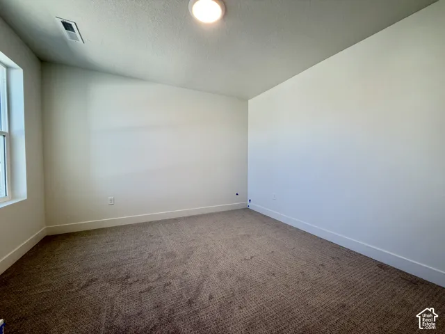 Recessed lighting, neutral wall tones, window for natural light, and textured carpeting