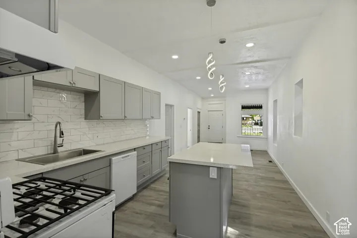 Kitchen featuring light gray cabinetry, stainless steel sink with gooseneck faucet, white subway tile backsplash, and light-toned wood-finish flooring