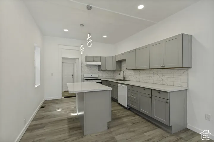 Kitchen featuring gray cabinetry, light countertops, subway tile backsplash, and wood-finish flooring