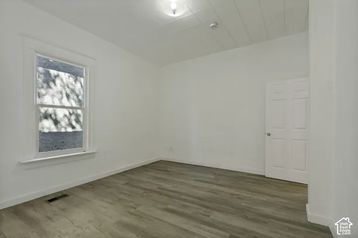 Wood-finish flooring, white paneled door, and a double-hung window with white trim