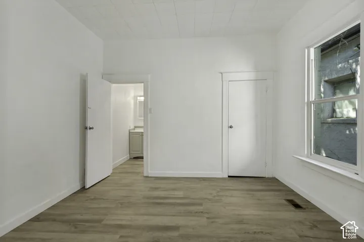 Neutral wall color, wood-finish flooring, white trim, double-hung window, and a paneled ceiling