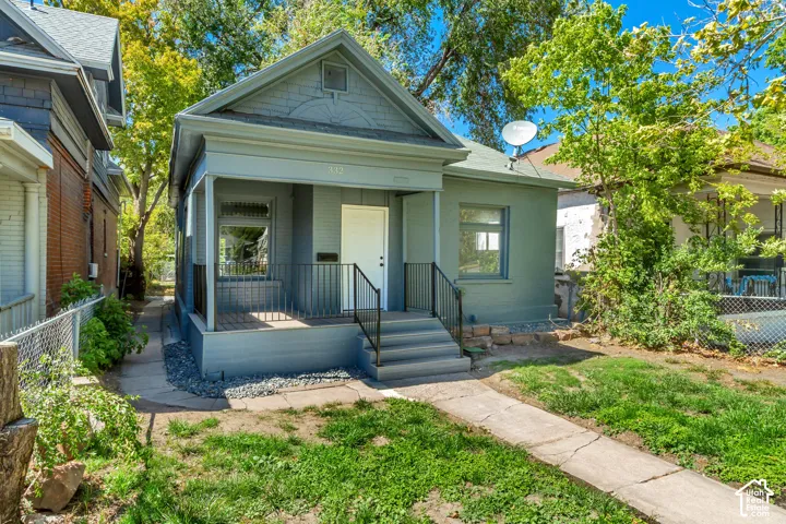 Gable roofline, covered front porch, concrete walkway, and landscaped front yard