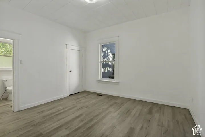 Neutral wall paint, wood-finish flooring, single window, recessed lighting, and a white interior door