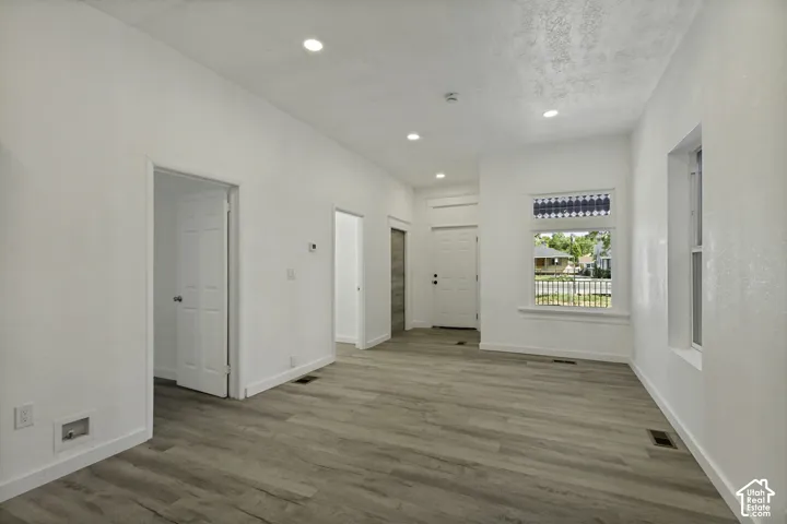 Wood-finish flooring, recessed lighting, and white walls create a bright and open atmosphere