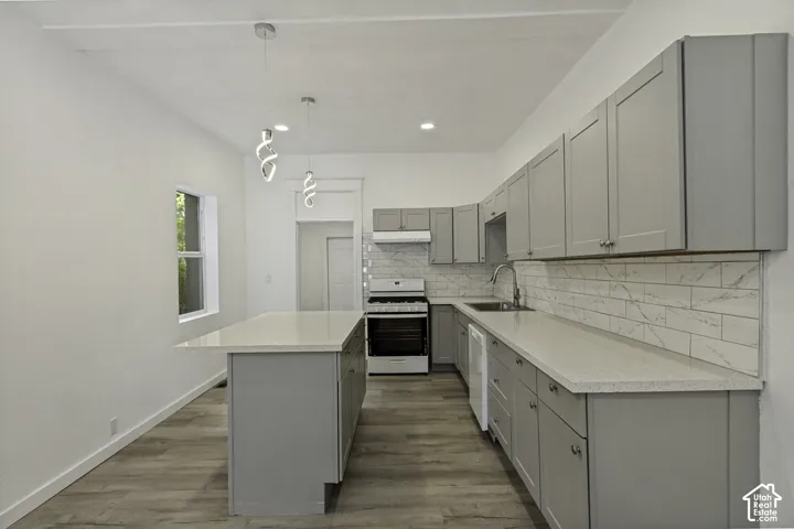 Kitchen featuring shaker-style cabinetry, light-toned countertops, a full suite of appliances, and wood-finish flooring