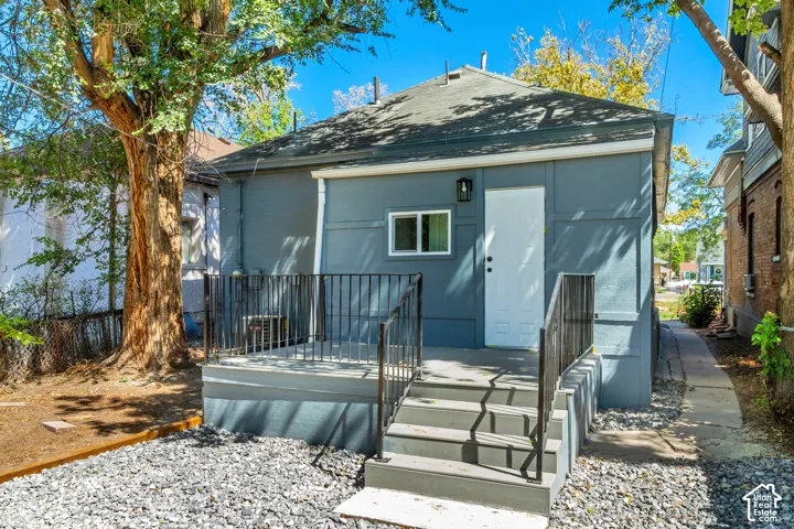 Exterior featuring a private entry, elevated deck with black railings, and a gravel ground cover